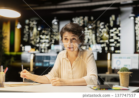 Woman joining a remote webinar from desk using laptop and headset, interacting with participants. Person maintaining eye contact, exchanging ideas in a chat that promotes networking. Woman joining a remote webinar from desk using laptop and headset, interacting with participants. Person maintaining eye contact, exchanging ideas in a chat that promotes networking. 137747557