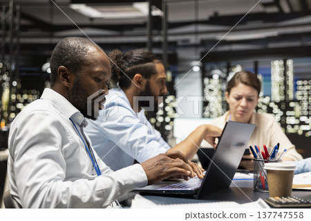Working together, laptop and management executives in office doing business meeting to plan project. Collaborating, device and teamworking colleagues doing research analysis for startup organization 137747558