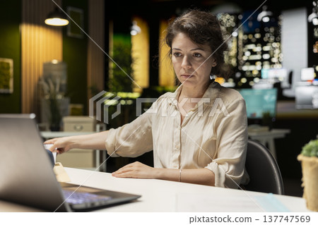 Engaged executive manager researching market data and developing strategy to meet business goals, using spreadsheets for proofreading. Late night work in a multinational company. Engaged executive manager researching market data and developing strategy to meet business goals, using spreadsheets for proofreading. Late night work in a multinational company. 137747569