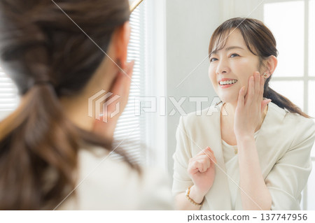 Woman applying makeup in the mirror 137747956