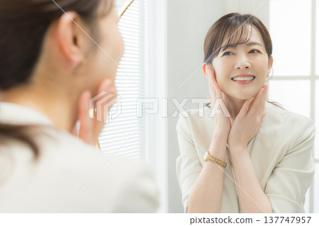 Woman applying makeup in the mirror 137747957