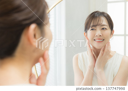 Woman applying makeup in the mirror Woman applying makeup in the mirror 137747998