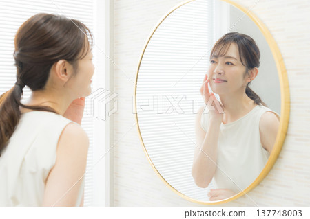 Woman applying makeup in the mirror Woman applying makeup in the mirror 137748003