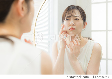 一個女人看著鏡子困擾著 137748047