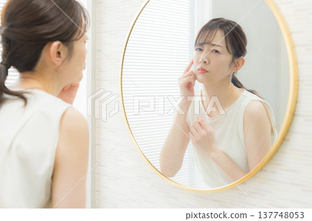 A woman troubled watching a mirror A woman troubled watching a mirror 137748053