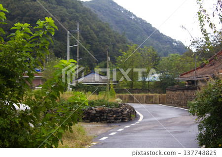 This is a rural road scene on a cloudy day. This is a rural road scene on a cloudy day. 137748825