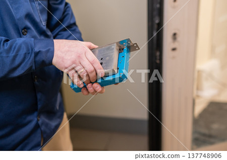 The technician installs a smart electronic lock on the front door. 137748906