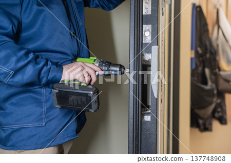 The technician installs a smart electronic lock on the front door. 137748908