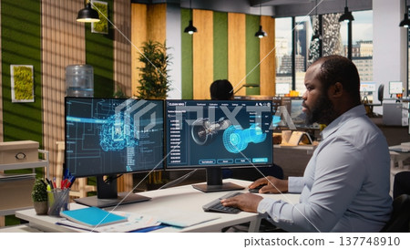 Engineer in office working on wind turbine component CAD design using artificial intelligence. African american man doing digital modeling of wind energy generator part using AI, camera A 137748910