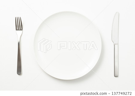Plates and cutlery against a white background Plates and cutlery against a white background 137749272