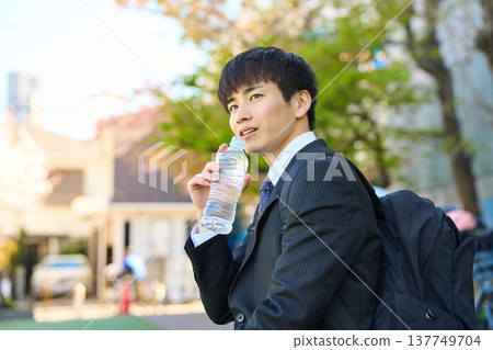 一位新晉商人外出拜訪客戶時,在公園裡補充水分,臉上露出笑容。 (上半身) 一位新晉商人外出拜訪客戶時,在公園裡補充水分,臉上露出笑容。 (上半身) 137749704