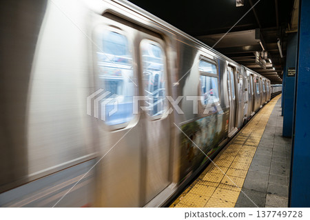 New York City subway train arriving with motion blur at Broadway Lafayette Street station in Manhattan. Urban underground transportation scene with yellow platform edge, steel columns, and metro 137749728