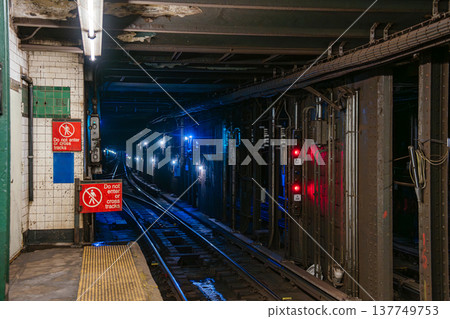 Close view of New York City subway tracks and underground tunnel with warning sign at West 4 Street Washington Square station. Urban public transportation infrastructure showing rails, signal lights Close view of New York City subway tracks and underground tunnel with warning sign at West 4 Street Washington Square station. Urban public transportation infrastructure showing rails, signal lights 137749753
