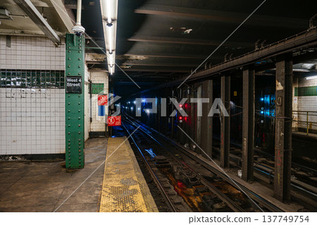 Dark underground New York City subway tunnel with red signal lights and railway tracks at West 4 Street station. Industrial metro infrastructure with warning signs and urban transit system details. Dark underground New York City subway tunnel with red signal lights and railway tracks at West 4 Street station. Industrial metro infrastructure with warning signs and urban transit system details. 137749754