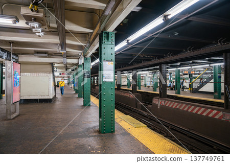 A wide view of West 4 Street subway station shows platforms, steel columns and tracks in Manhattan. The New York City subway system operates as a major public transportation network. A wide view of West 4 Street subway station shows platforms, steel columns and tracks in Manhattan. The New York City subway system operates as a major public transportation network. 137749761
