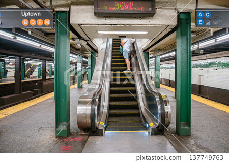 An escalator connects platforms at West 4 Street subway station in Manhattan. Line signs for B, D, F, M and A, C, E trains mark the New York City transit system. An escalator connects platforms at West 4 Street subway station in Manhattan. Line signs for B, D, F, M and A, C, E trains mark the New York City transit system. 137749763