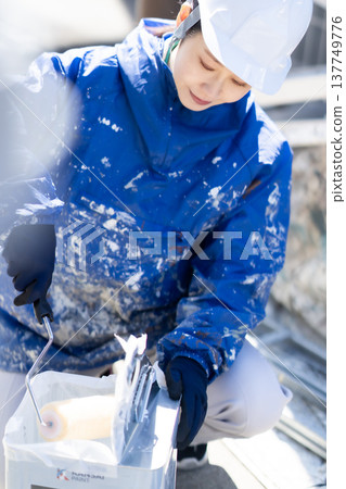 一位女油漆工將滾筒放在溶劑之間進行準備。 一位女油漆工將滾筒放在溶劑之間進行準備。 137749776