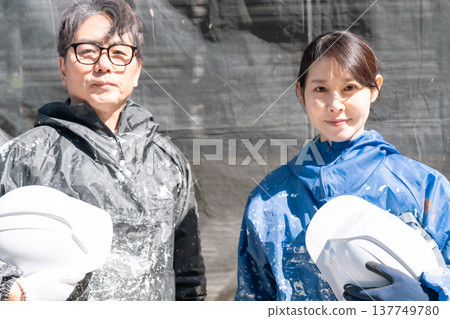值得信賴的技能。經驗豐富的男女工匠與年輕的男女工匠共同在外牆塗裝工地工作。 值得信賴的技能。經驗豐富的男女工匠與年輕的男女工匠共同在外牆塗裝工地工作。 137749780