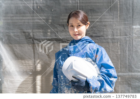 一位活躍在建築業的女工匠。一位身穿沾滿油漆的工作服、微笑的女油漆工。 一位活躍在建築業的女工匠。一位身穿沾滿油漆的工作服、微笑的女油漆工。 137749783