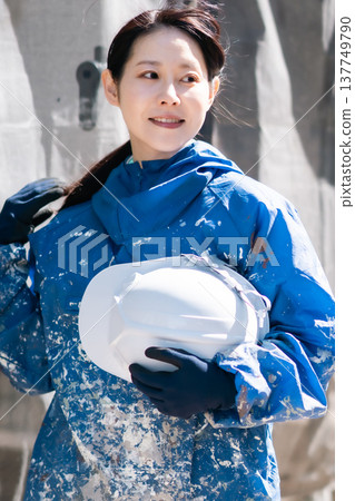 A female craftswoman active in the construction industry. A female painter smiling in her paint-stained work clothes. A female craftswoman active in the construction industry. A female painter smiling in her paint-stained work clothes. 137749790