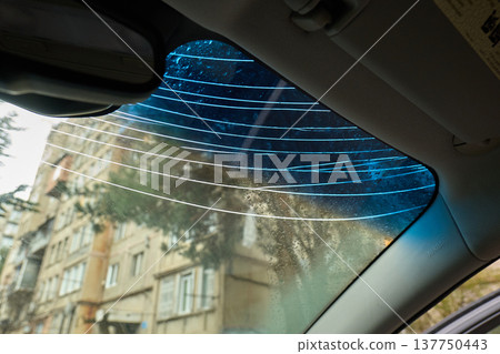 Interior shot of a damaged glass windshield with blue tint and multiple impact cracks 137750443