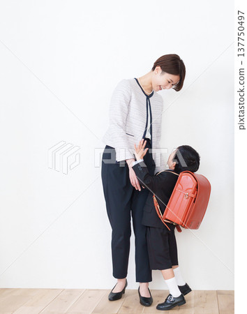 一名背著書包的小學生和他的家人(為了參加入學典禮,他們都穿著正式西裝)。 一名背著書包的小學生和他的家人(為了參加入學典禮,他們都穿著正式西裝)。 137750497