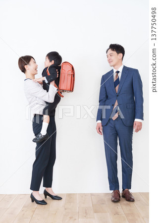 A first-grade elementary school boy with a schoolbag on his back and his family (for the entrance ceremony, formal suits). 137750498