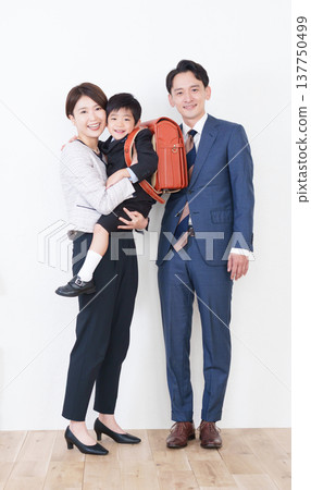 A first-grade elementary school boy with a schoolbag on his back and his family (for the entrance ceremony, formal suits). 137750499