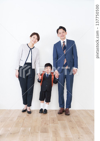 一名背著書包的小學生和他的家人（為了參加入學典禮，他們都穿著正式西裝）。 137750500
