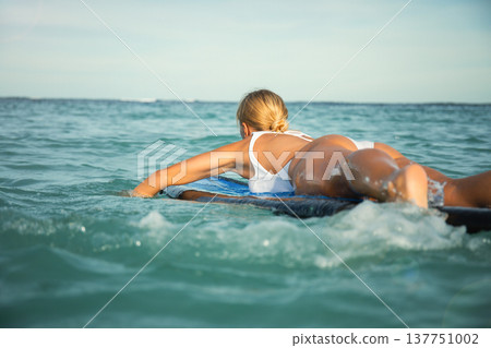 Surfer preparing to ride a wave in calm ocean water Surfer preparing to ride a wave in calm ocean water 137751002