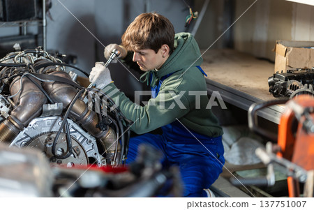 Young auto mechanic repairing an engine in garage Young auto mechanic repairing an engine in garage 137751007