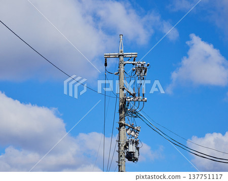 A winter scene of blue sky, city utility poles, and power lines. 137751117