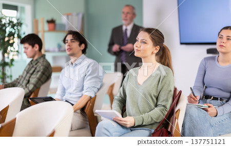 Students listening in lecture hall with professor in background 137751121