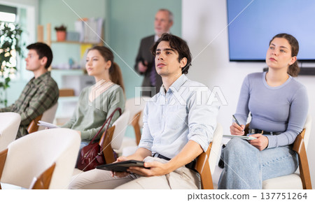 Students are listening to a lecture, and the teacher is standing in the background Students are listening to a lecture, and the teacher is standing in the background 137751264