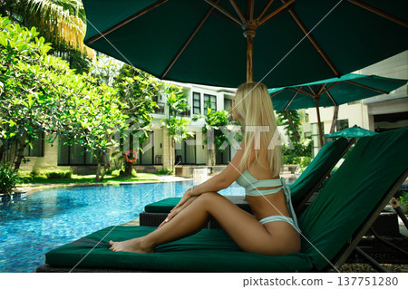 Woman enjoys the serene atmosphere by the pool Woman enjoys the serene atmosphere by the pool 137751280