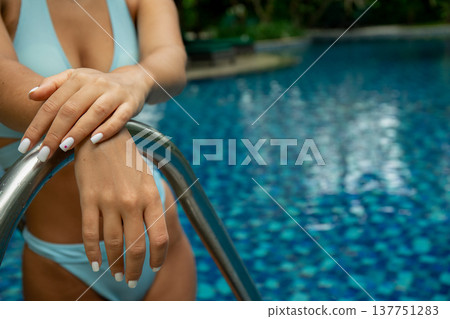 Woman enjoying leisure time at a tranquil poolside Woman enjoying leisure time at a tranquil poolside 137751283