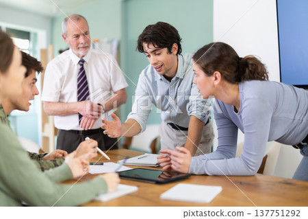 Students solving problems at table with teacher in background Students solving problems at table with teacher in background 137751292