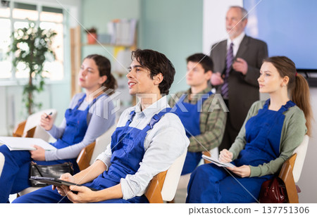 Young male student worker listening to lecture with teacher in background Young male student worker listening to lecture with teacher in background 137751306