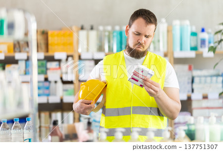 Young man builder chooses paracetamol at pharmacy 137751307