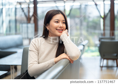 Happy asian woman resting head on hand with elbow on backrest sitting leaning on sofa couch in cafe. 137751467