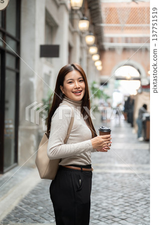 Smiling asian woman carrying bag holding coffee walking or standing sideway in shopping mall market. Smiling asian woman carrying bag holding coffee walking or standing sideway in shopping mall market. 137751519