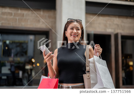Pretty asian woman holding shopping bag and phone while walking or standing at cafe in a mall market 137751566