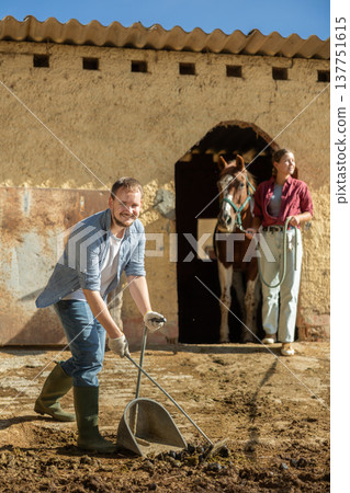 Young man cleans manure near stable 137751615