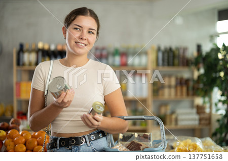 Young woman choosing canned food in grocery store 137751658