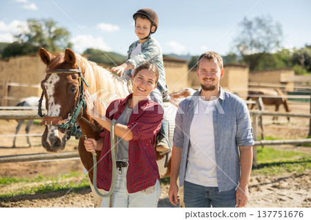 Man and woman leading horse with boy on horseback Man and woman leading horse with boy on horseback 137751676