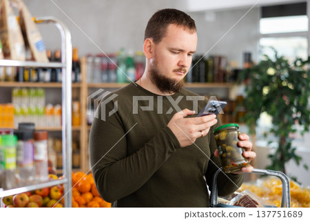 Man scanning a jar of pickles Man scanning a jar of pickles 137751689