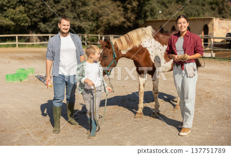 Father, mother and son riding horse together at small horse farm Father, mother and son riding horse together at small horse farm 137751789