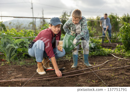 Woman and son planting seeds on farm 137751791
