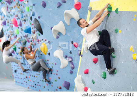 Young man practicing rock climbing on climbing wall 137751818