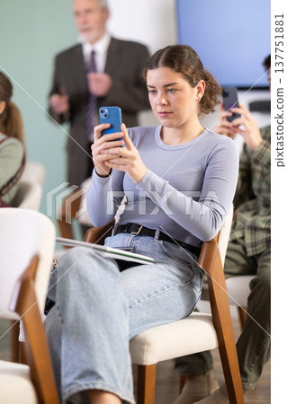 Young female student scans QR code or takes photo, teacher in background 137751881
